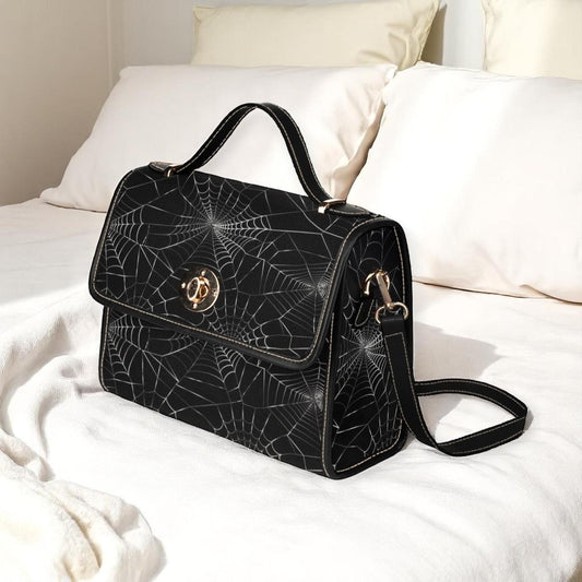 a black handbag sitting on top of a white bed