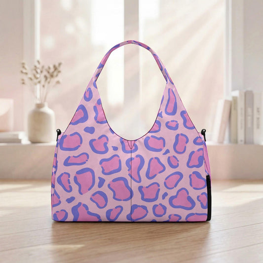 A pink and purple leopard print handbag is displayed on a wooden surface, with a window and some books visible in the background.