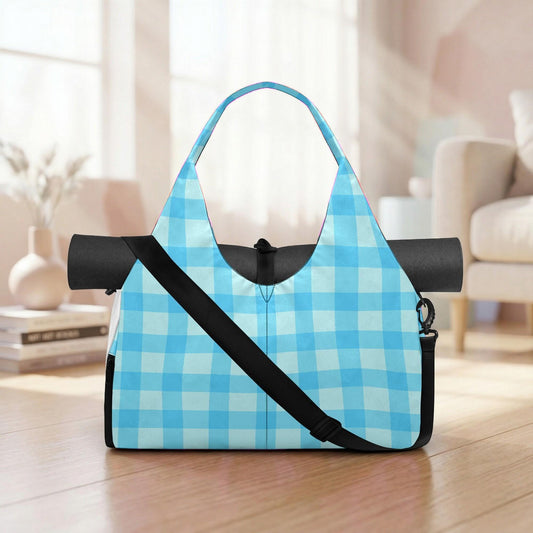 A blue and white checkered tote bag with a black strap is placed on a wooden floor in a room with a window and a couch.