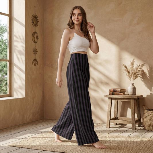 A woman in a white crop top and striped pants stands in a room with a wooden table and a vase of flowers.