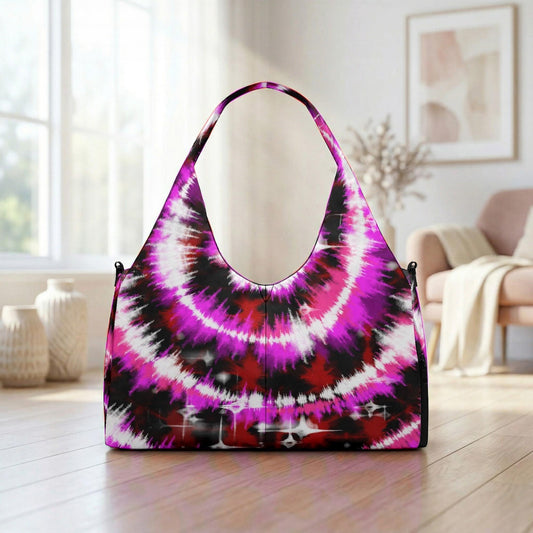A vibrant, tie-dye handbag with a striking pattern of pink, purple, and black colors is displayed on a wooden floor in a room with a window and a couch.