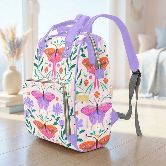 A colorful backpack with a floral pattern and butterflies printed on it, sitting on a wooden surface.