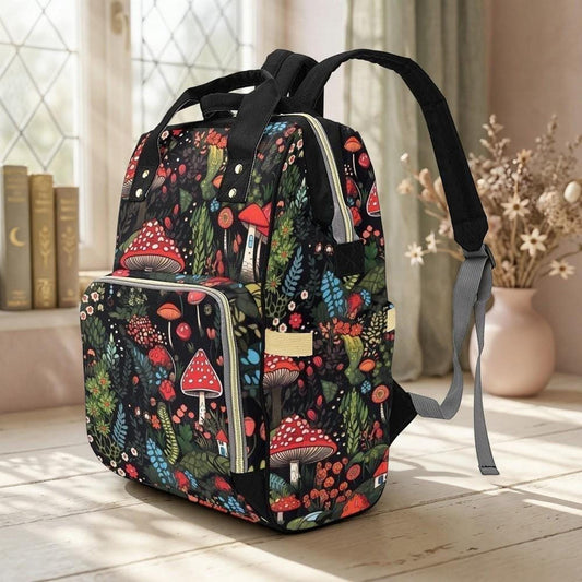 A black backpack with a colorful mushroom and forest print stands on a light wooden floor, angled slightly to the right, with a window and vase in the background.