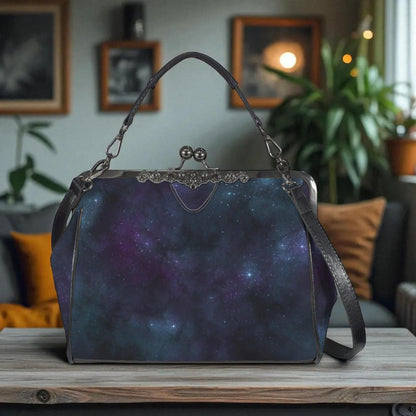 A handbag with a starry galaxy print design is displayed on a wooden surface, with a cozy indoor setting visible in the background.