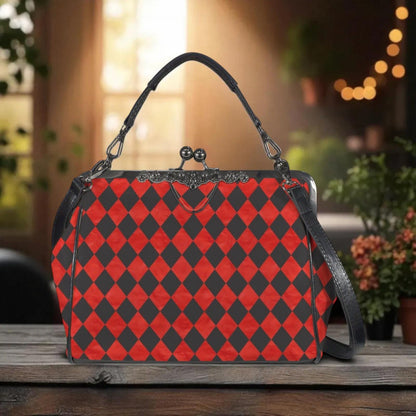 A red and black checkered handbag with a black leather strap is displayed on a wooden surface, with a blurred background of greenery and lights.