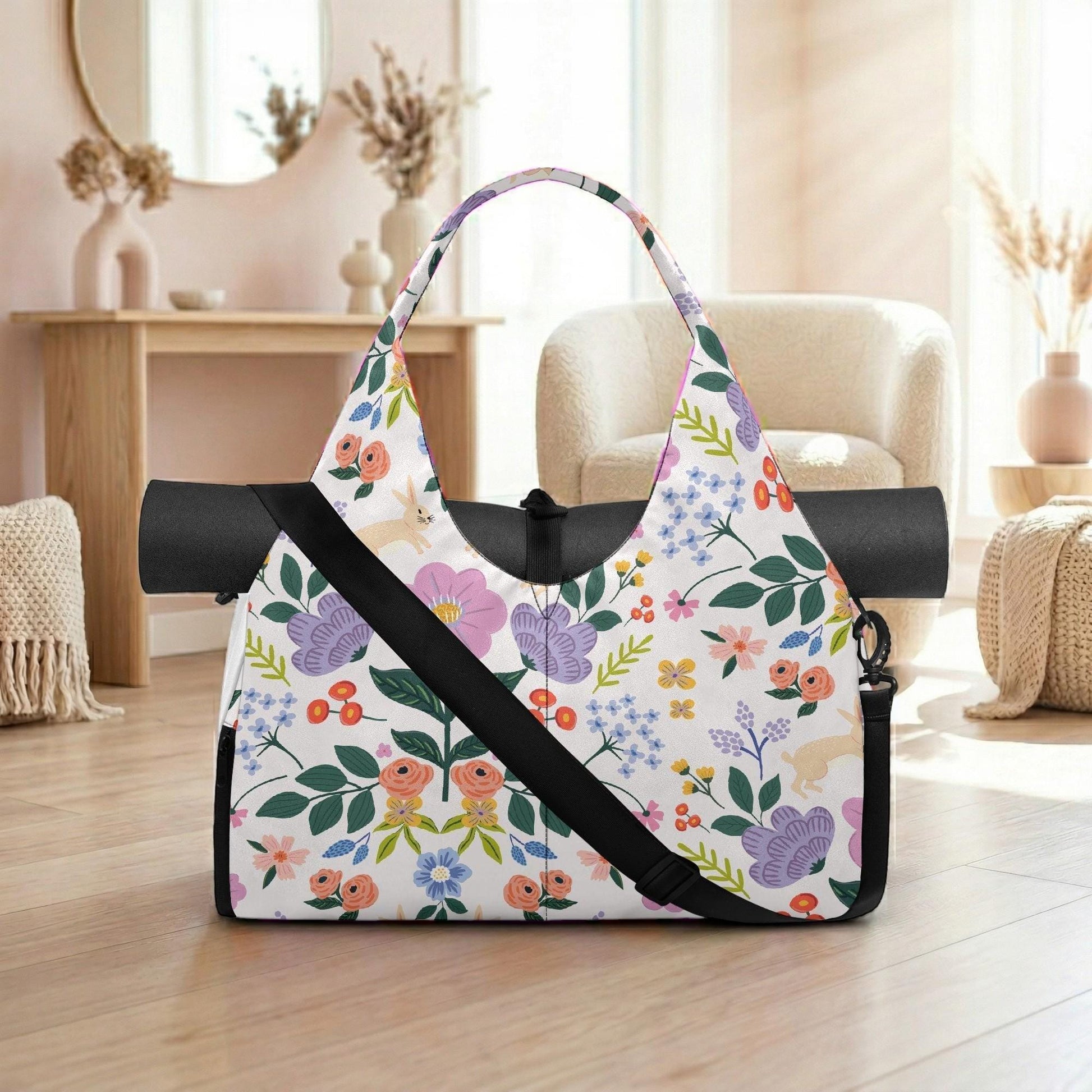 A colorful floral patterned tote bag with a black strap is displayed on a wooden floor in a room with a mirror, vases, and a chair.