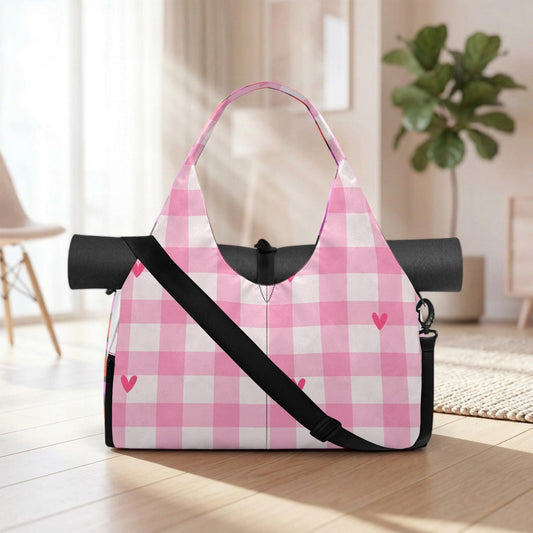 A pink and white checkered bag with a black strap and heart-shaped embellishments is placed on a wooden floor in a room with a potted plant in the background.