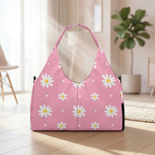 A pink handbag with white daisy patterns is placed on a wooden floor in a room with a potted plant in the background.