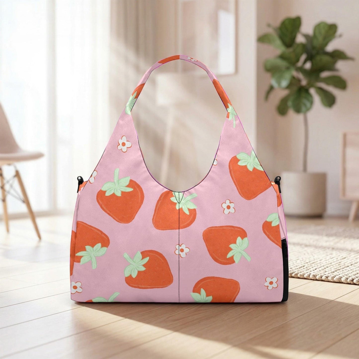 A pink handbag with a strawberry pattern is placed on a wooden floor in a room with a potted plant in the background.
