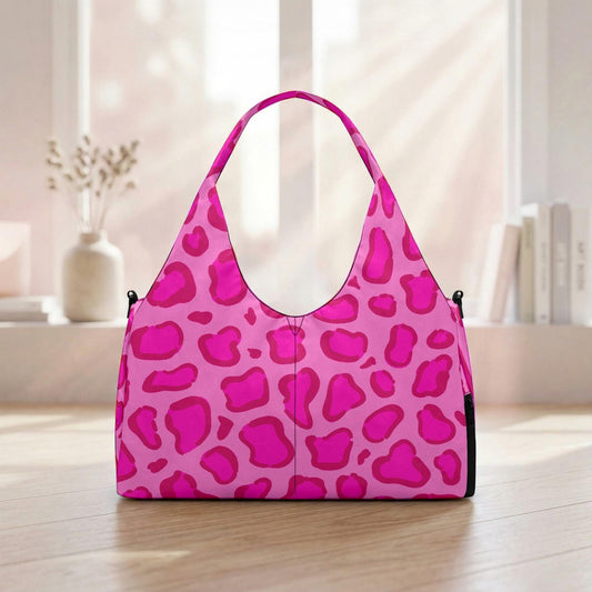 A pink leopard print handbag is displayed on a wooden floor in front of a window.