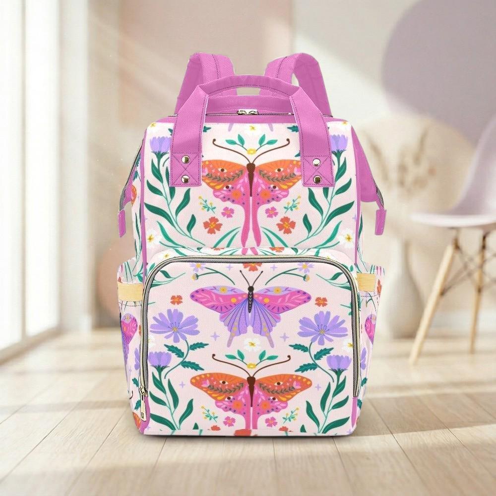 A colorful and vibrant backpack with a floral and butterfly design, featuring pink and purple colors, is displayed on a wooden floor against a white wall.