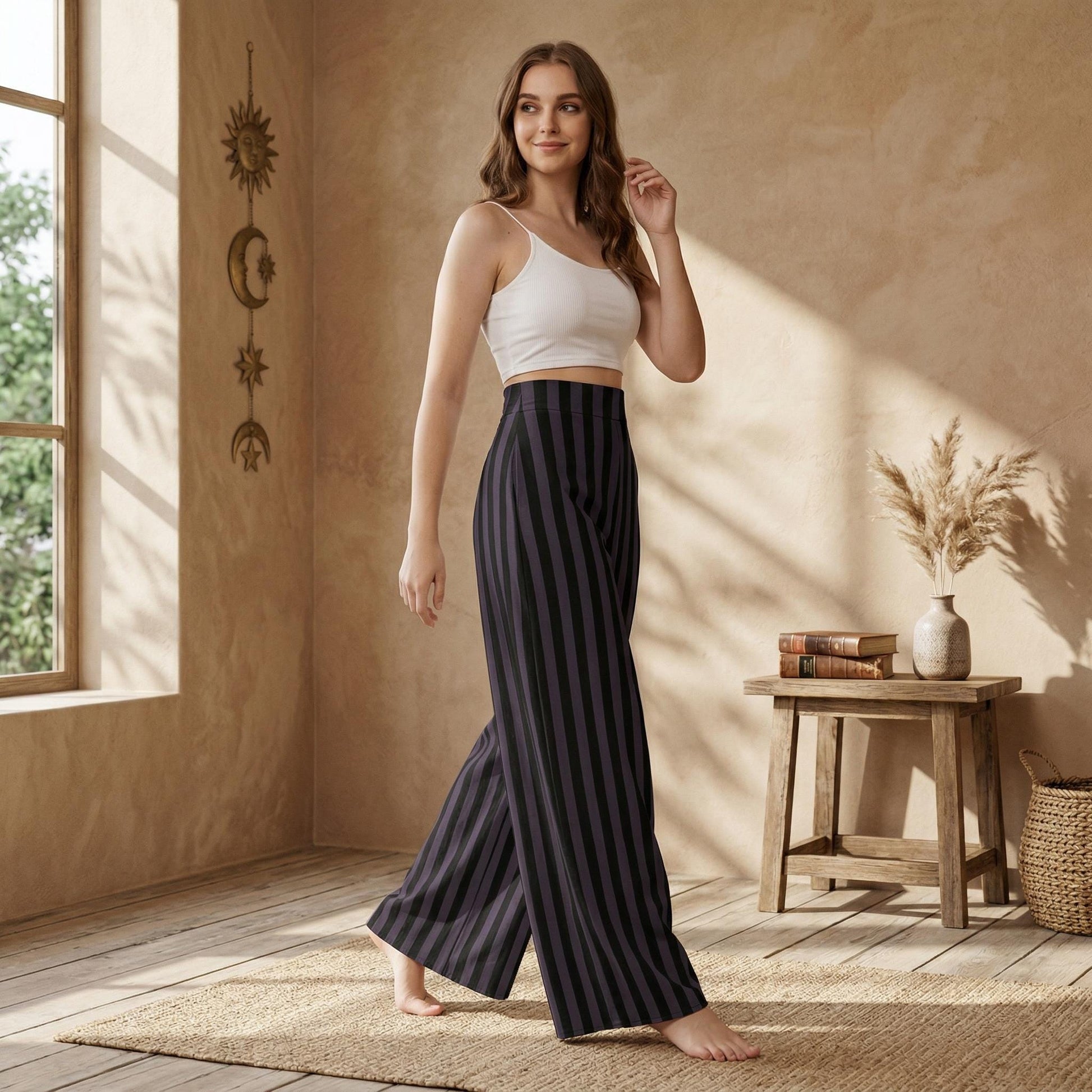 A woman in a white crop top and striped pants stands in a room with a wooden table and a vase of flowers.