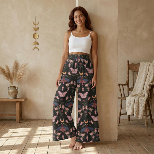 A woman wearing a white crop top and wide-leg pants with a floral print stands in a room with a wooden floor and a beige wall.