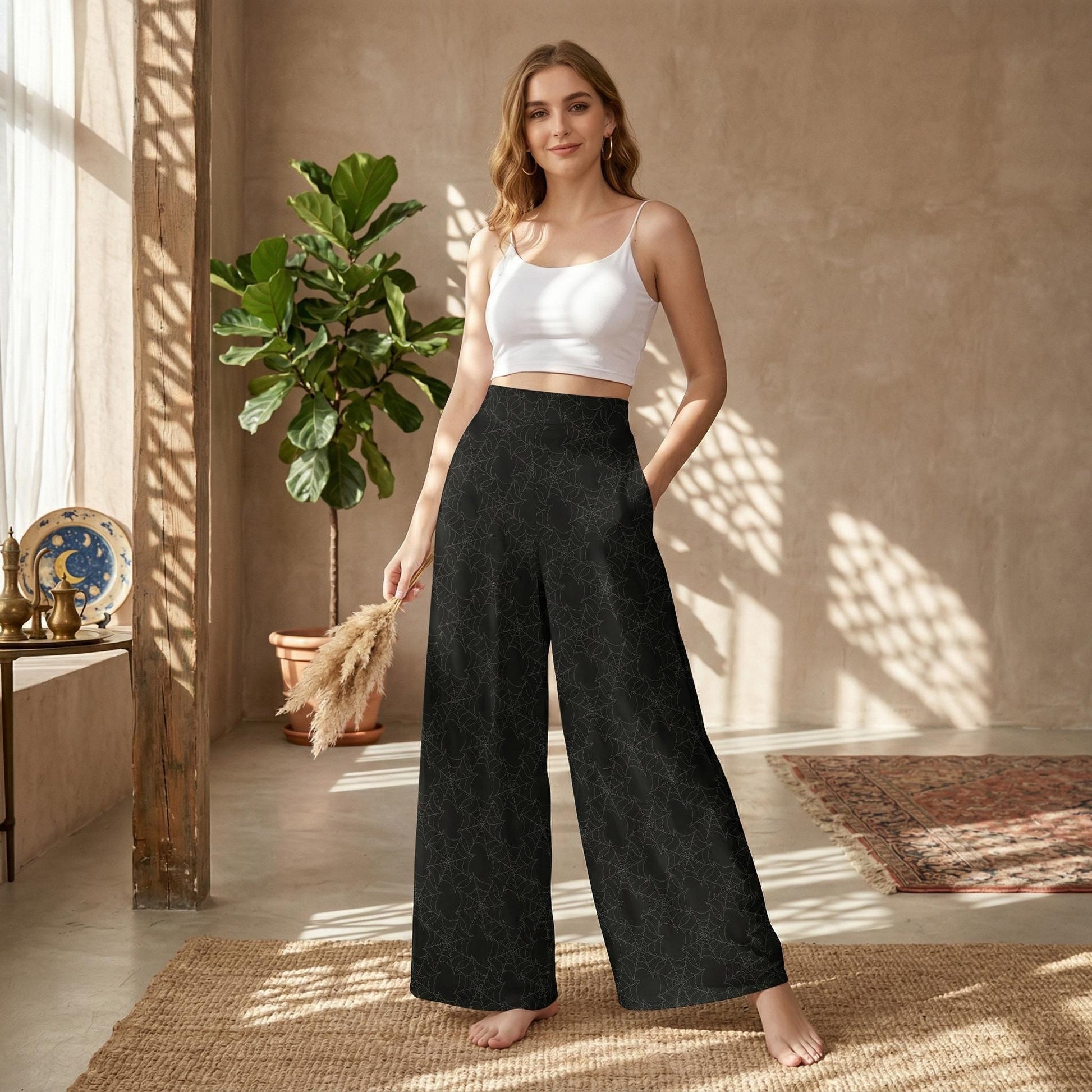 A woman wearing a white crop top and black patterned wide-leg pants stands in a room with a potted plant and a rug.
