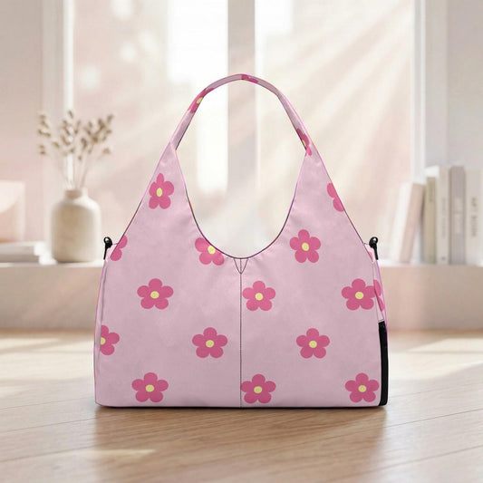 A pink handbag with a floral pattern is displayed on a wooden surface, with a window and some books visible in the background.