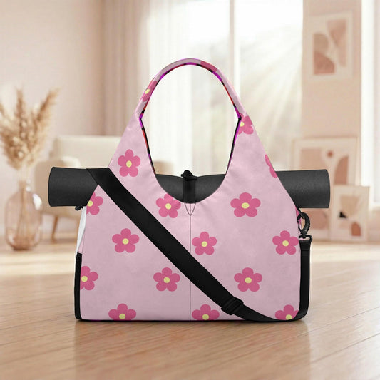 A pink tote bag with a floral pattern is placed on a wooden surface, with a vase of dried flowers in the background.