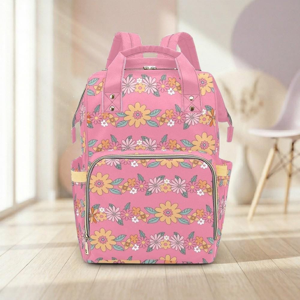 A pink backpack with a floral pattern is displayed on a wooden floor in a room with a chair visible in the background.