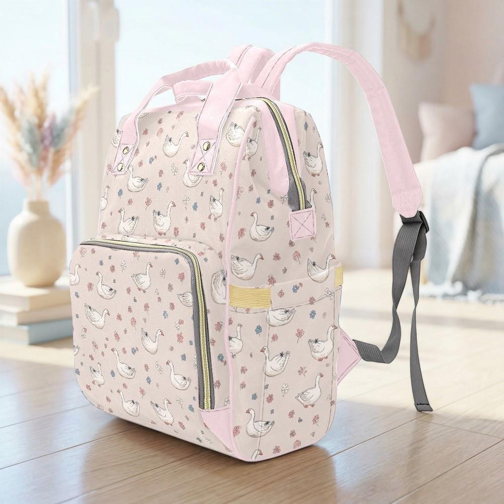 A pink backpack with a pattern of ducks on a wooden surface, with a vase of flowers in the background.