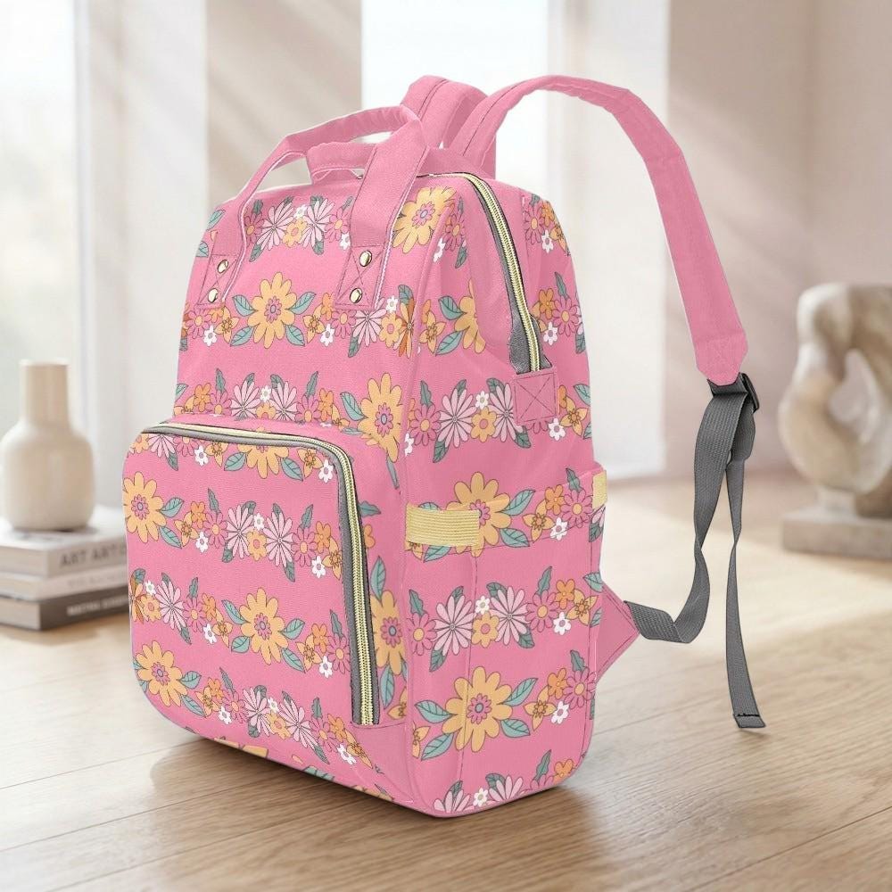 A pink backpack with a floral pattern is sitting on a wooden surface.
