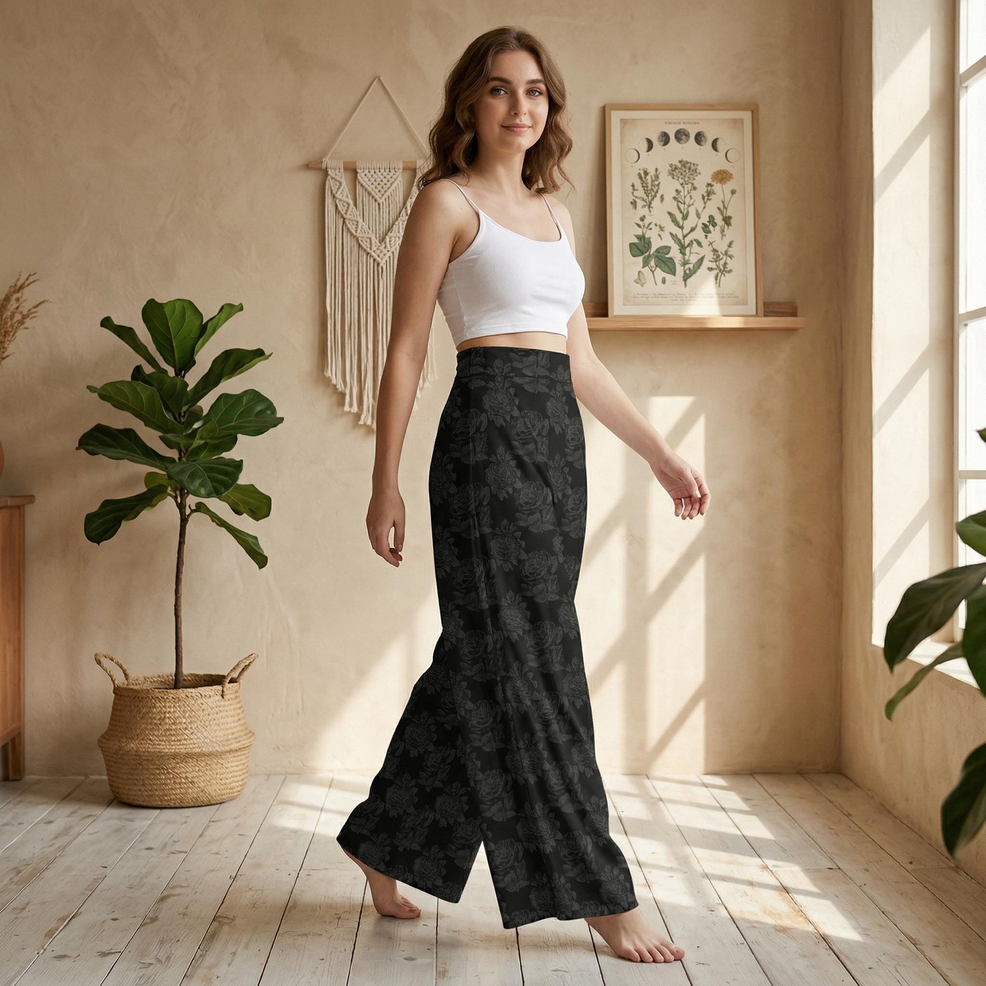 A woman in a white crop top and black floral pants stands in a room with a potted plant, a woven basket, and a framed plant on the wall.