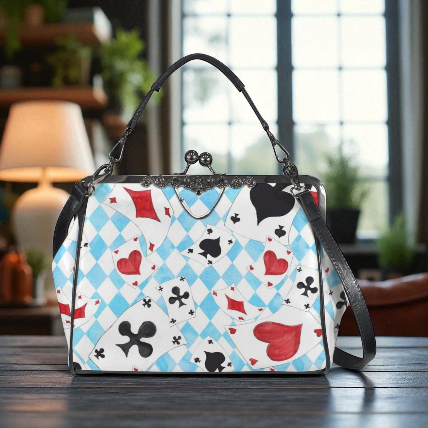 A handbag with a unique pattern of playing cards printed on it, sitting on a wooden surface.