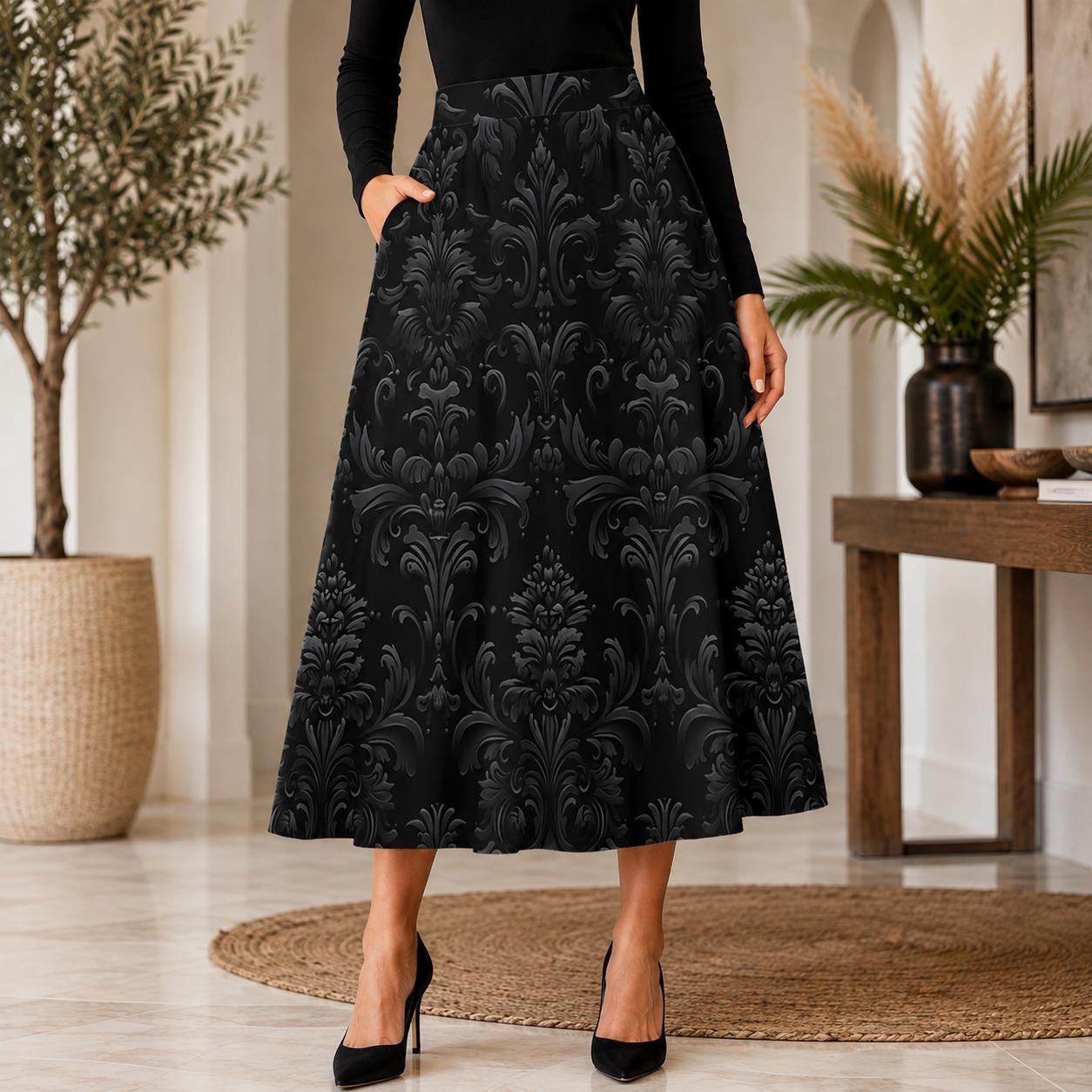 Black damask print midi skirt with large charcoal baroque medallions, shown in a full A line shape from a high waistband to mid calf, with one hand resting in a side pocket.