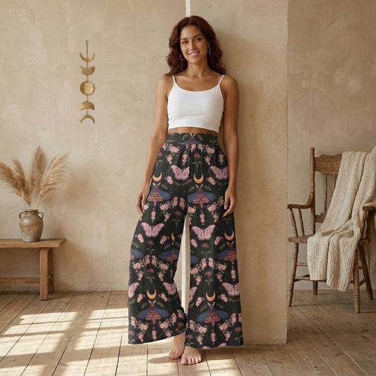 A woman wearing a white crop top and wide-leg pants with a floral print stands in a room with a wooden floor and a beige wall.