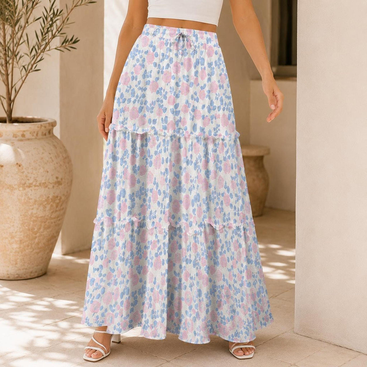 Lower body view of the tiered maxi skirt with a white base and blue and pink floral pattern, paired with white sandals.