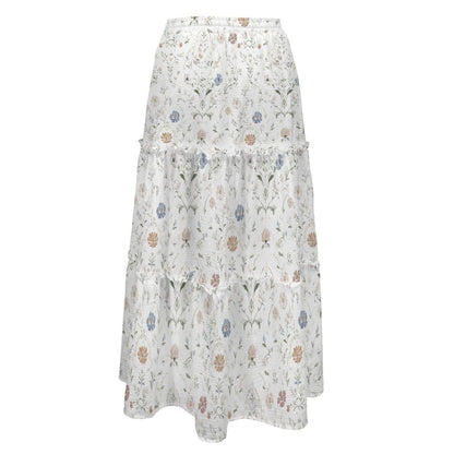 A long, white, high-waisted tiered maxi skirt with an all-over delicate floral botanical print in muted blue, pink, and green tones.