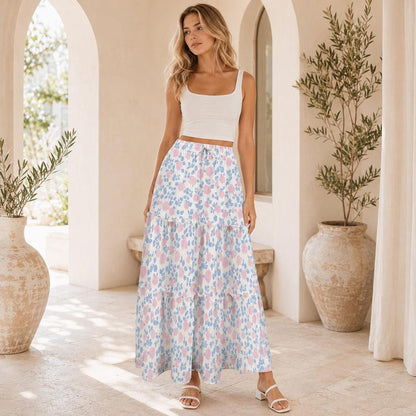 Full-length shot of the model wearing the white tank top and pink and blue patterned tiered maxi skirt in an arched hallway.