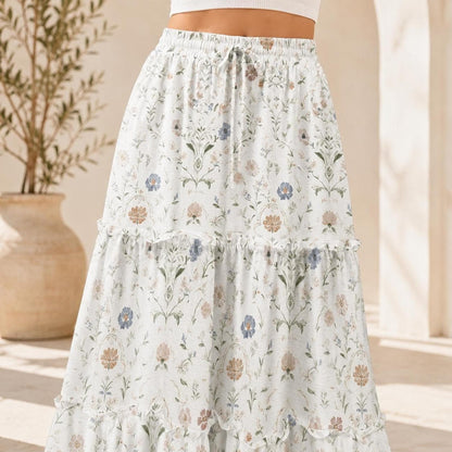 Close-up of the upper portion of a white tiered maxi skirt featuring a delicate blue and brown floral botanical pattern.