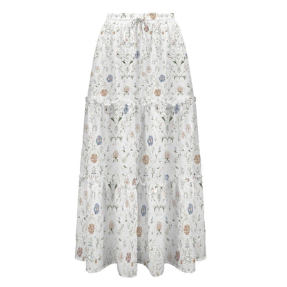 Studio shot of a white tiered maxi skirt featuring a delicate multicolored floral botanical pattern against a white background.