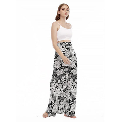 A model stands against a plain white background wearing a white crop top and high-rise black and white floral palazzo trousers.