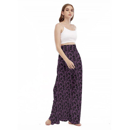 A three-quarter view of a model against a plain white background wearing the purple floral wide-leg trousers and a white spaghetti-strap crop top.
